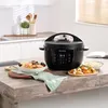 A black Instant Pot multicooker is displayed on a wooden table, surrounded by prepared food dishes, in a kitchen setting. Anteprima dell’immagine prodotto