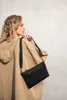 A woman is wearing a tan hoodie and carrying a black crossbody bag. Produktbild-Vorschau