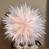A white paper star lantern with small lights inside, placed on a chair. Podgląd zdjęcia produktu