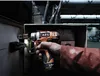 A person's hand is holding a cordless drill near an electrical box with exposed wires. Náhľad obrázku produktu