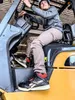 A person wearing work boots is sitting in a forklift. Náhľad obrázku produktu