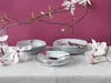 A table setting with porcelain plates and bowls decorated with pink flowers, with a branch of magnolia flowers in the foreground. Náhľad obrázku produktu
