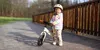 A young child stands on a wooden bridge with a balance bike. Náhled obrázku produktu