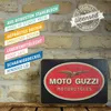 A vintage-style tin box with the Moto Guzzi logo, placed on a wooden surface against a brick wall background. Informational text overlays are present on the left side of the image. Náhled obrázku produktu