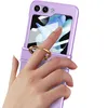 A hand wearing a ring is holding a purple flip phone case with a ring stand. Produktbild-Vorschau
