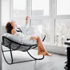 A woman relaxing in a rocking chair in a bright room with large windows. Produktbild-Vorschau