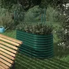 A green raised garden bed filled with herbs sits in a garden next to a wooden bench. Voir les images du produit