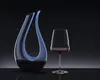 A clear glass decanter and wine glass filled with red wine, set against a dark, gradient background. Produktbild-Vorschau