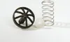 A black wheel-like object, a white ball, and a silver spring are arranged on a white background. Produktbild-Vorschau