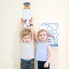 Two children are standing next to a height chart in a room. Náhľad obrázku produktu