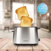 A stainless steel toaster with two slices of toast popping out, set on a wooden table with a blurred kitchen background. Produktbild-Vorschau