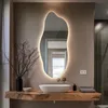 A modern bathroom vanity with a live-edge wood countertop, a vessel sink, and an illuminated, irregularly shaped mirror. Produktbild-Vorschau