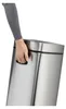 A person's hand is holding the handle of a metallic silver trash can. Podgląd zdjęcia produktu