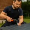 A man is using an electric sheet metal shear to cut through corrugated metal outdoors. Podgląd zdjęcia produktu