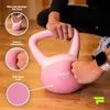 A person is holding a pink kettlebell on a wooden floor, with close-up insets highlighting product features. Produktbild-Vorschau