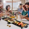 A group of friends enjoying a meal together around a table with a grill. Voir les images du produit