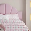A close-up view of a pink upholstered bed with patterned bedding. Produktbild-Vorschau