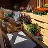 A person is relaxing on a pallet bench on a wooden balcony, reading a book, surrounded by potted plants. Náhľad obrázku produktu