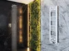 A modern bathroom with a black marble shower, a living green wall, and a white towel radiator. Náhled obrázku produktu