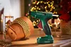 A hot glue gun is shown next to a terracotta pot decorated with gold rope, with a Christmas tree in the background. Produktbild-Vorschau