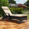 A rattan sun lounger with beige cushions is placed on a wooden deck in a garden setting. Anteprima dell’immagine prodotto