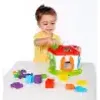 A young child plays with a colorful shape sorter toy on a white table. Produktbild-Vorschau