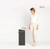 A woman stands next to a trash can, with height measurements indicated. Voir les images du produit