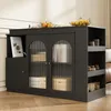 A black sideboard with glass doors, displaying books and decorative items, situated in a room with wooden flooring and a hint of a sofa in the background. Oranges and lemons are visible on top. Podgląd zdjęcia produktu