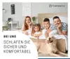 A family and their dog are relaxing on a bed in a bedroom setting. Produktbild-Vorschau