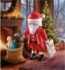 Santa Claus figure in a festive Christmas setting with a fireplace and Christmas tree. Náhľad obrázku produktu