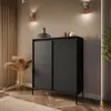 A modern black dresser with fluted doors and a sliding panel, placed in a well-decorated room with ambient lighting and decorative elements. Produktbild-Vorschau