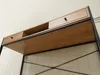 A close-up view of a wooden desk with black metal frame, showing drawers and shelving. Podgląd zdjęcia produktu