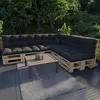 An outdoor patio setting with a sectional sofa made of pallets and black cushions, a coffee table, and a rug. Anteprima dell’immagine prodotto