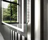 A close-up view of a modern illuminated mirror with LED lights, reflecting an outdoor scene through a large window. Produktbild-Vorschau