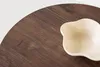 A close-up view of a beige bowl on a dark wood surface. Produktbild-Vorschau