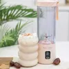 A portable blender and a smoothie are displayed on a table with some dates and greenery in the background. Podgląd zdjęcia produktu