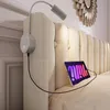 A bed with a tufted headboard, a bedside lamp with a USB port, and a tablet charging. Náhled obrázku produktu