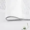 A close-up of a gray decorative ribbon with text printed on a white background. Produktbild-Vorschau