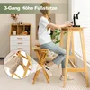 A woman sits on a bamboo bar stool at a bamboo bar table in a room with a white and wood cabinet in the background. A close-up inset shows a foot resting on a footrest. Produktbild-Vorschau