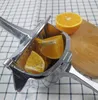A manual citrus juicer with orange slices inside, placed on a checkered tablecloth. Náhľad obrázku produktu