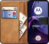A book-style phone case with cards and money inserted, next to a smartphone displaying the Motorola logo and product name. Náhľad obrázku produktu