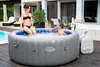 A couple relaxing in an inflatable hot tub on a wooden deck. Produktbild-Vorschau