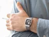 A person wearing a blue shirt and a silver digital watch. Voir les images du produit