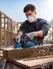 A man is using a Bosch power planer on a piece of wood at a construction site. Podgląd zdjęcia produktu