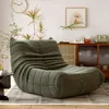 A green beanbag chair is placed on a striped rug in a living room setting, with a cabinet and decor in the background. Produktbild-Vorschau