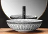 A patterned basin with a black faucet is shown in front of a mirror. Podgląd zdjęcia produktu