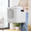 A person is holding a white cat litter box in a room. Náhled obrázku produktu
