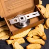 A cookie press attachment and freshly baked cookies are shown in a cardboard box. Produktbild-Vorschau