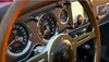Close-up of a vintage car's dashboard with gauges and a wooden steering wheel. Produktbild-Vorschau