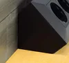 A close-up view of a black power strip with USB ports, placed in a corner where two walls meet, resting on a wooden floor. Produktbild-Vorschau